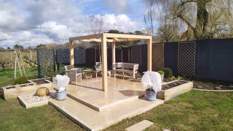 Finished timber pergola over a paved patio with planted sleeper beds