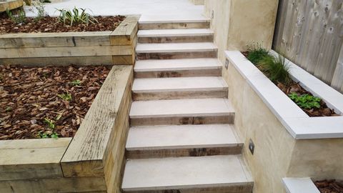 Stone steps with oak sleeper retaining walls through a landscaped bank